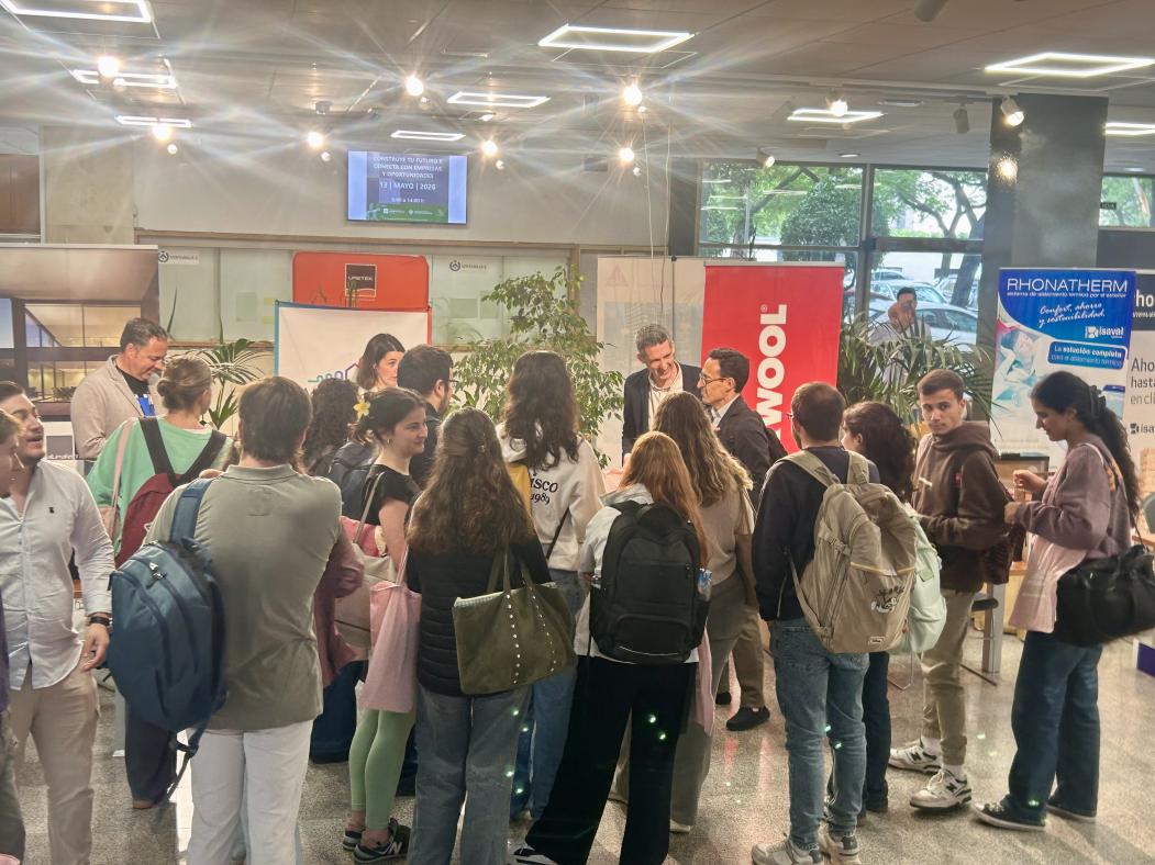 Asistentes en el hall de la escuela, mirando los distintos stands de las empresas y charlando entre ellos.