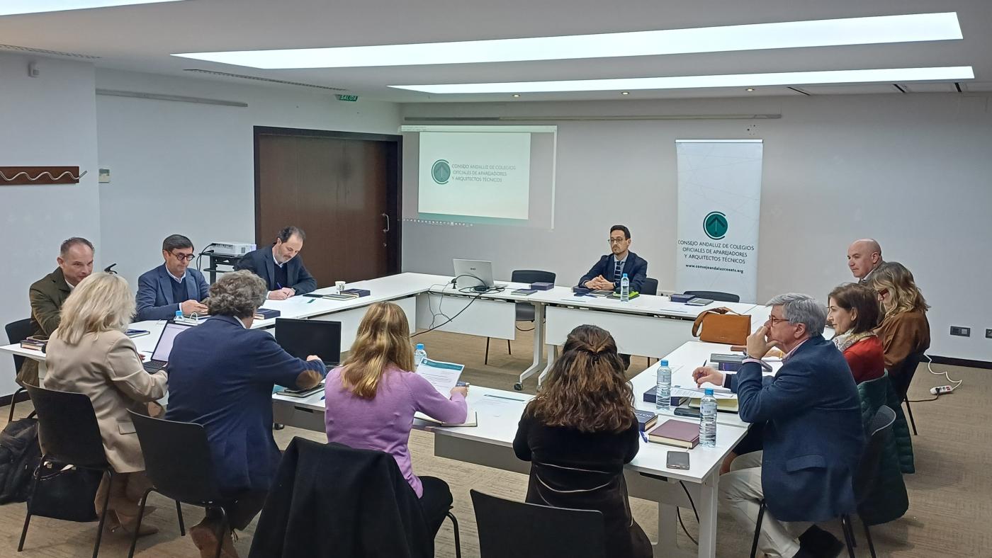 Fotografía de la reunión. Representantes reunidos en una sala alrededor de mesas dispuestas en forma de rectángulo.