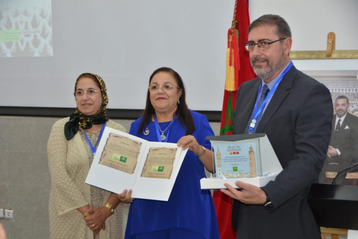 Fotografía del profesor Miguel ángel Tabales recogiendo el premio junto a dos mujeres de la organización del congreso.